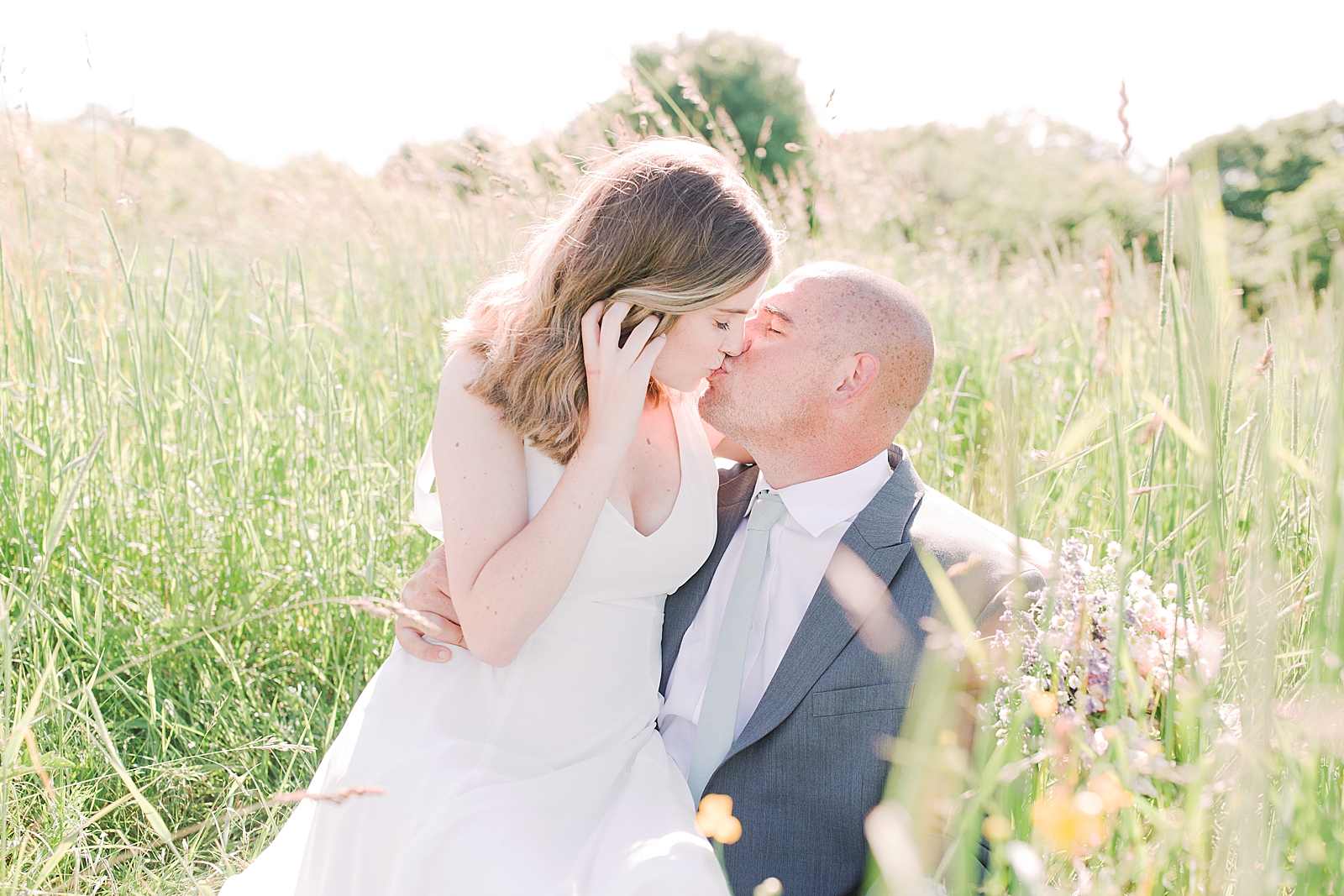 Max Patch Elopement Bride and Groom Sitting and Kissing in Tall Grass Photo