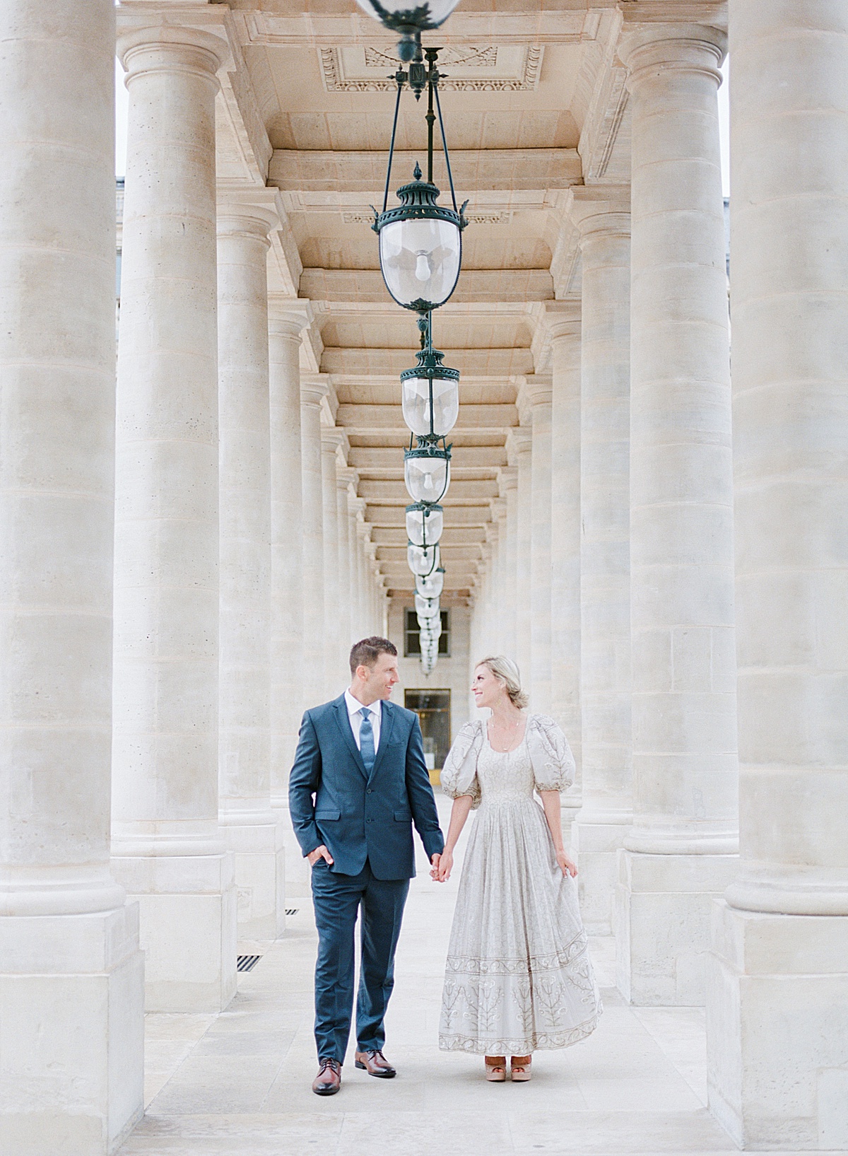 Palais Royal Engagement Couple holding hands walking through columns Photo