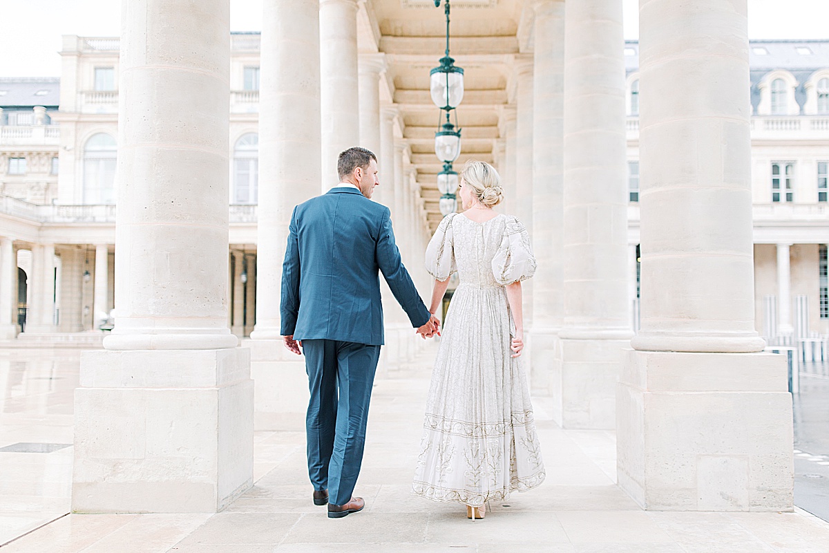 Palais Royal Engagement Couple walking away holding hands in between columns Photo