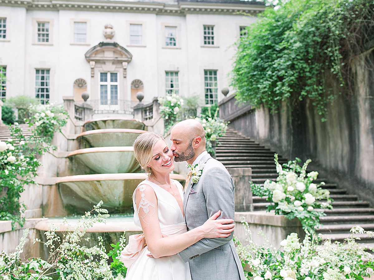 Swan House Wedding Groom Kissing Bride on Cheek in Front of Fountain Photo
