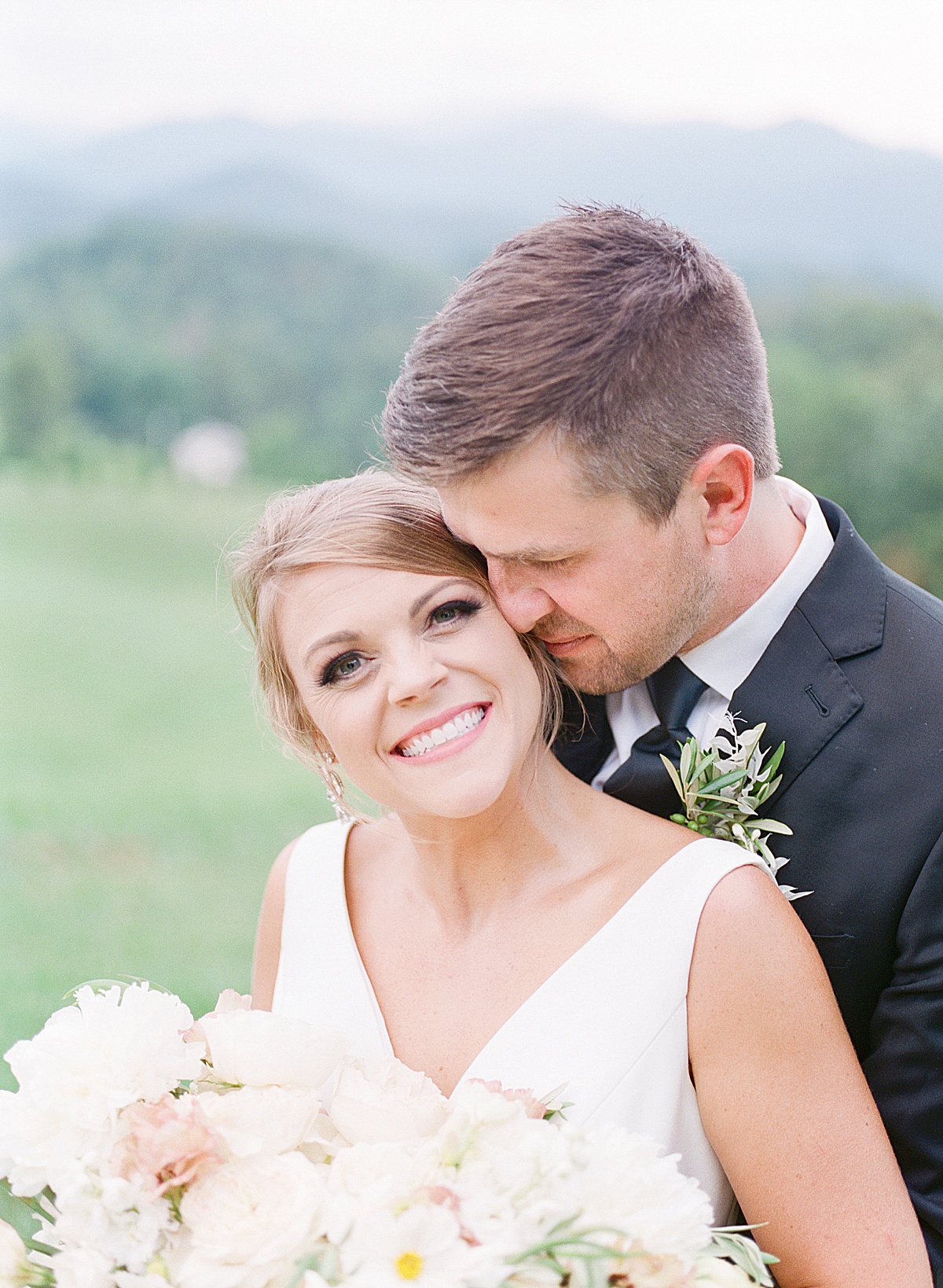 The Ridge Asheville Wedding Bride Smiling at Camera and Groom Snuggling in Photo