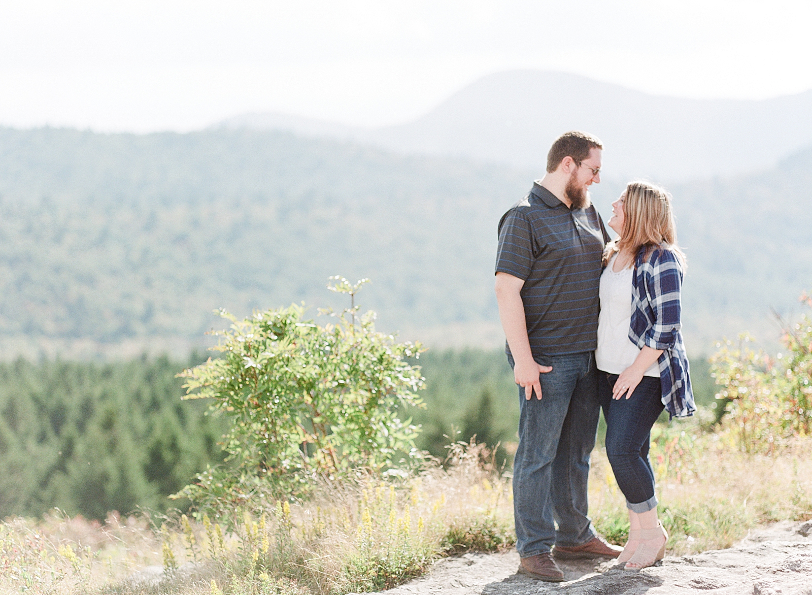 Blue Ridge Parkway Engagement Couple Smiling at each other with Mountain Background Photo