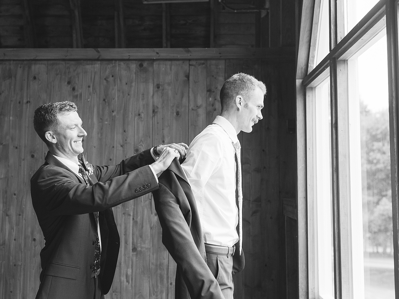 Dairy Barn Wedding Black and White of Best man putting grooms jacket on Photo