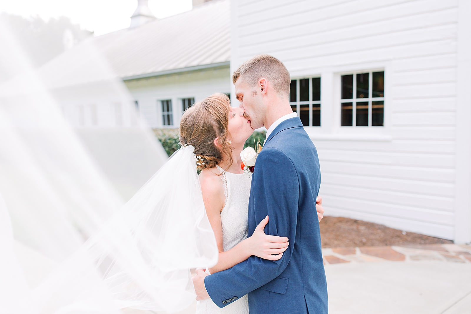 Dairy Barn Wedding Bride and Groom kissing with veil sweeping in front Photo