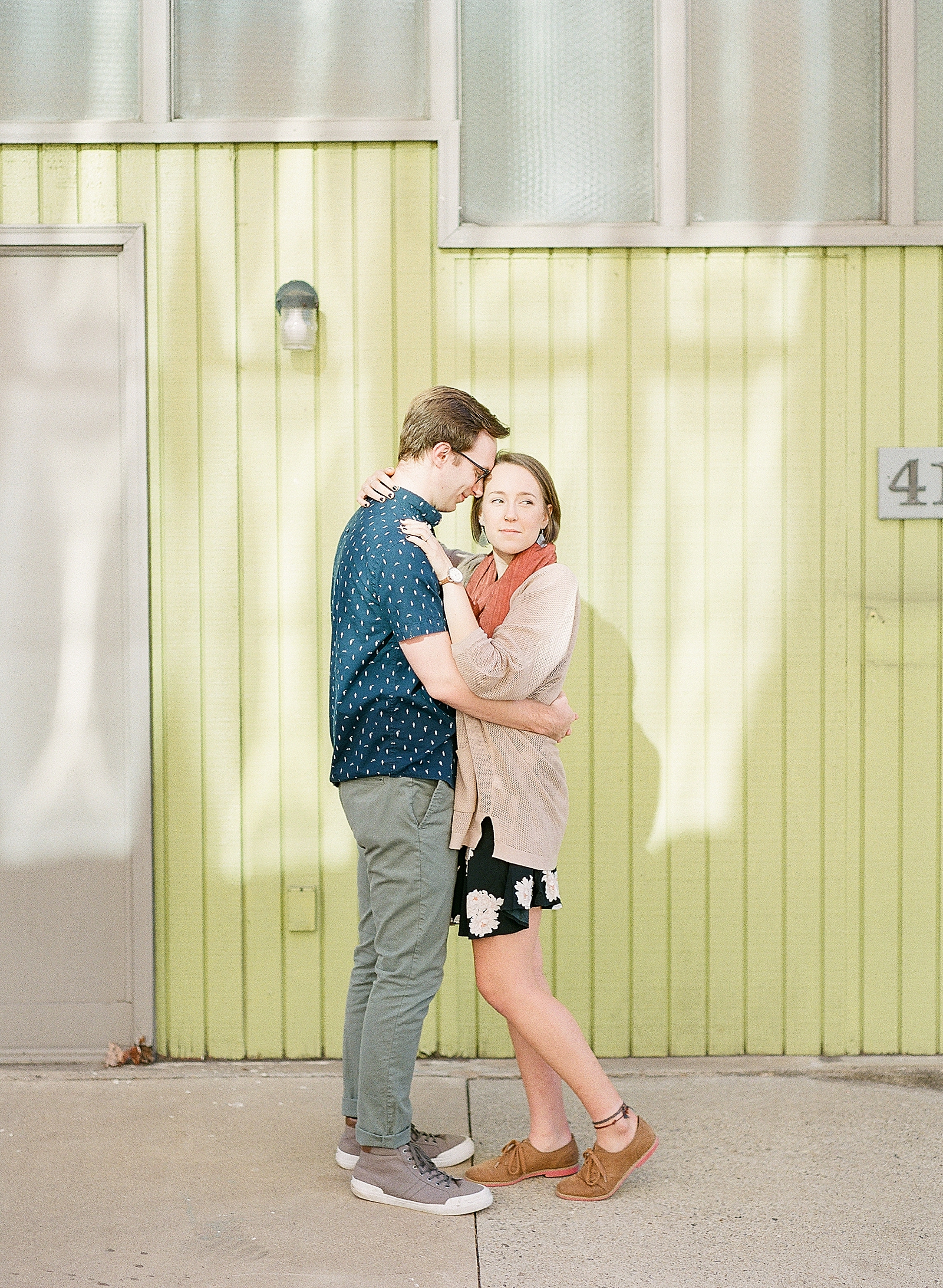 Downtown Asheville Engagement Session Couple hugging in front of green wall Photo