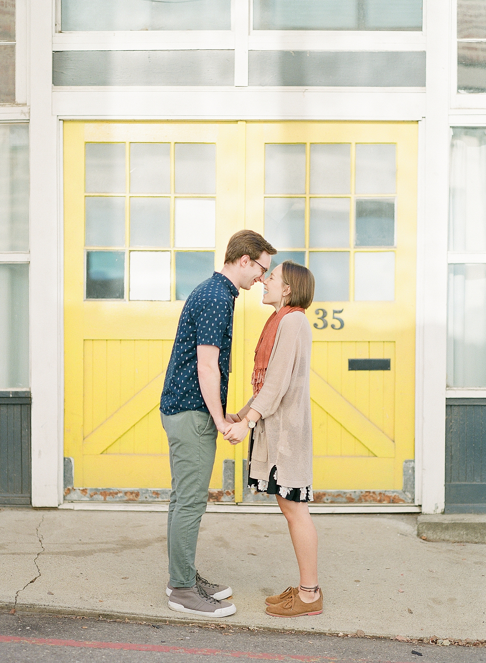 Downtown Asheville Engagement Session Couple Nose to Nose in front of yellow door Photo