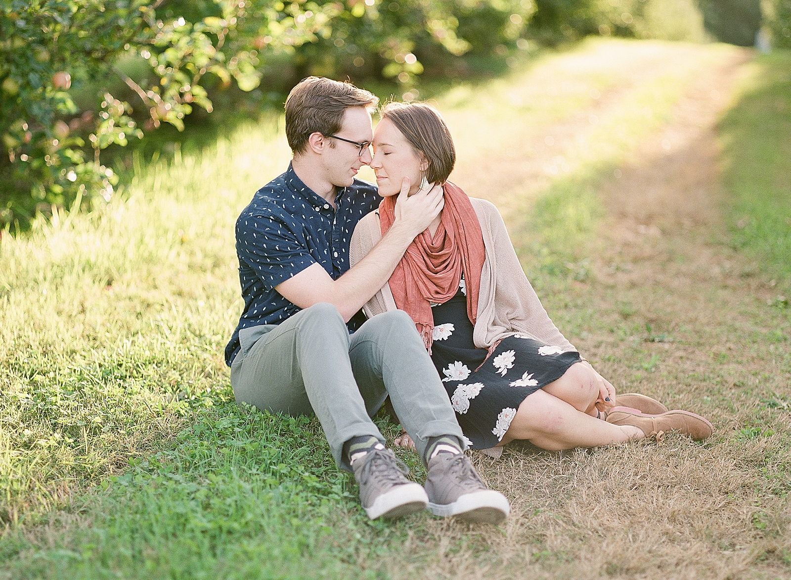 Downtown Asheville Engagement Session Couple Sitting in Grass Nose to Nose Photo
