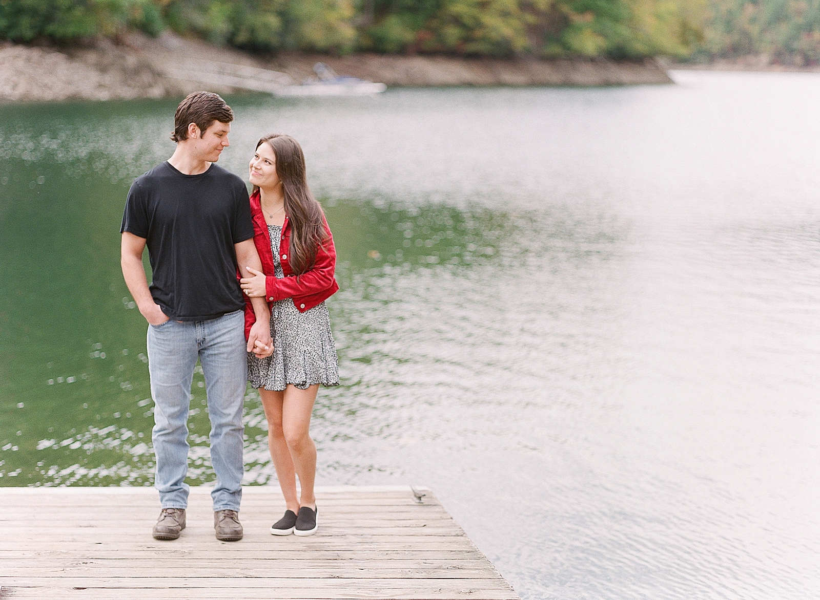 Mountaintop Engagement Couple smiling at each other on lake dock Photo 