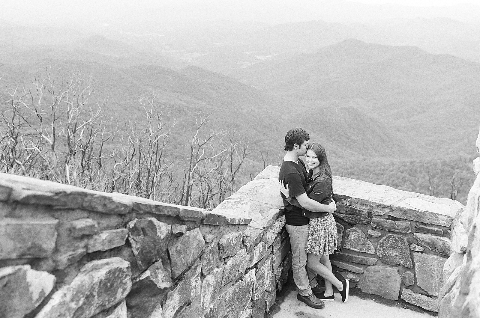 Mountaintop Engagement Black and white of couple hugging with mountains in background Photo 