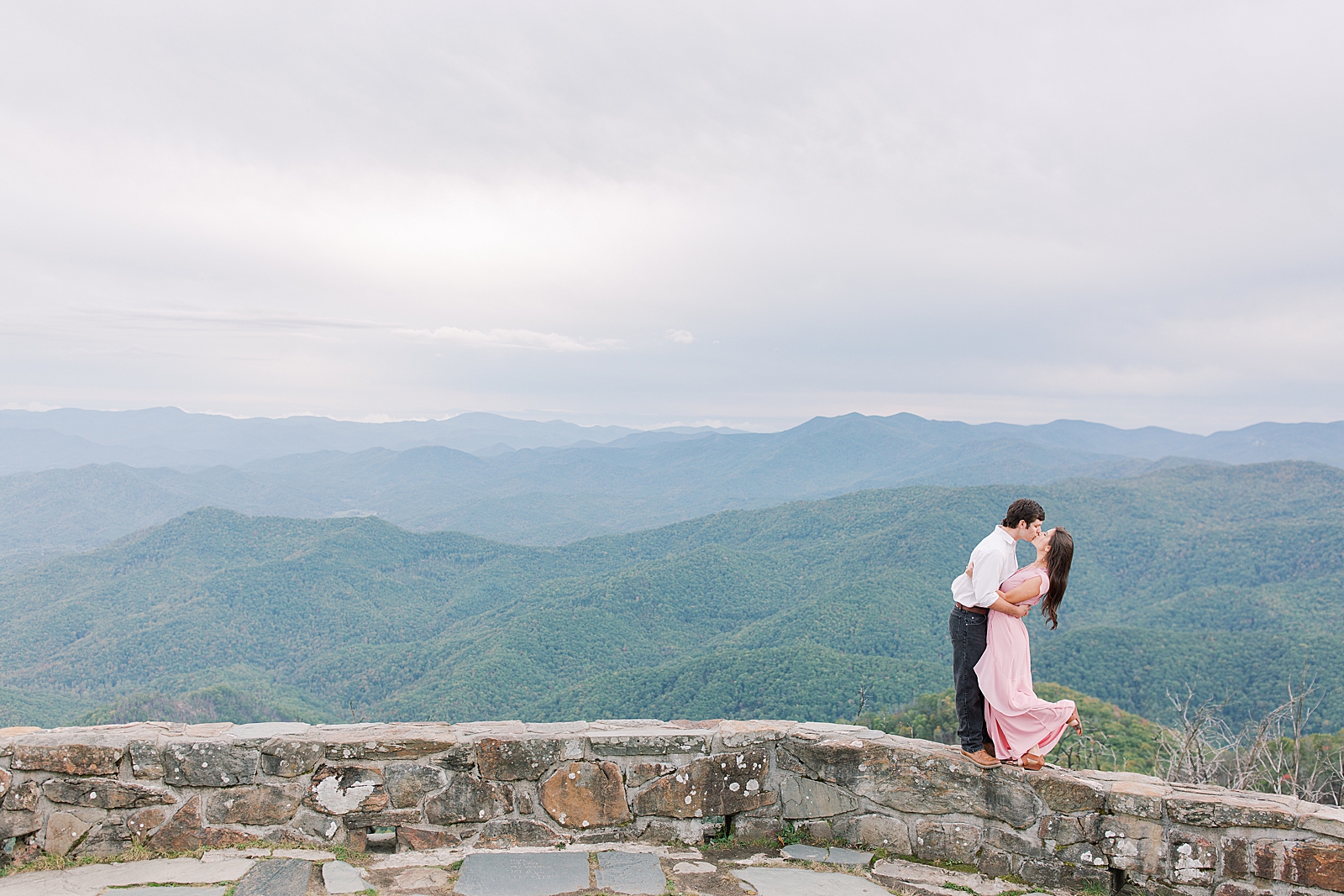 Mountaintop Engagement Couple Kissing on Wall Photo 