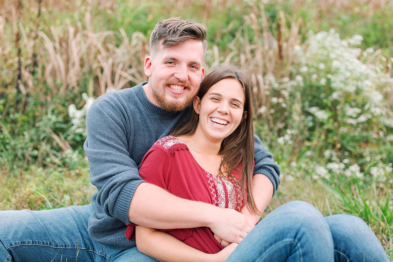  North Carolina Mountain Engagement Session Couple Smiling at Camera Sitting in Grass Photo