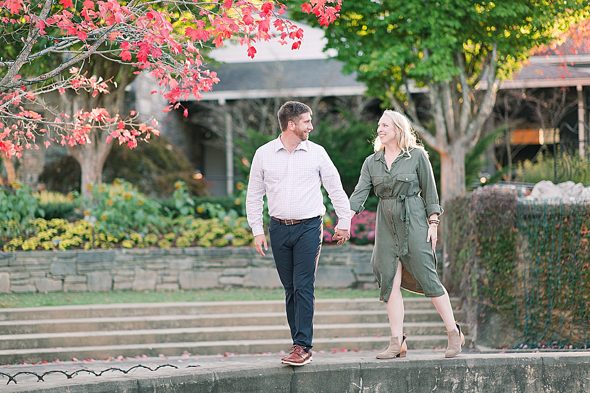 Asheville Arboretum Engagement Session Couple Walking on Wall Smiling at Each Other Photo