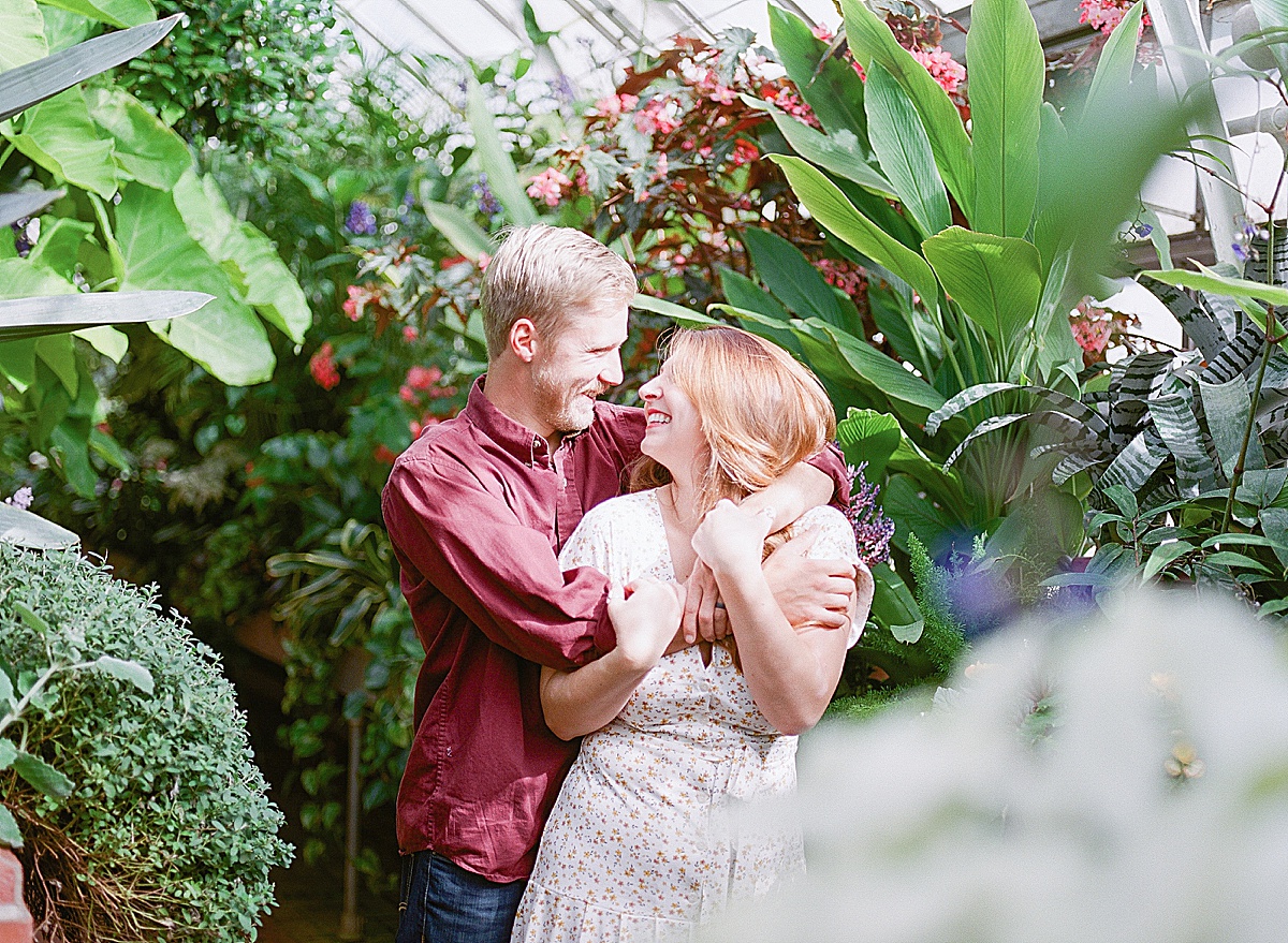 Couple hugging and smiling at each other in a greenhouse photo