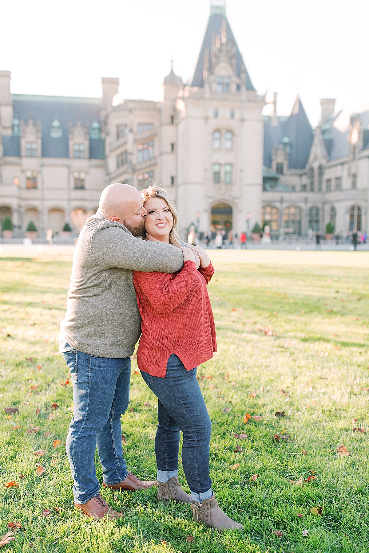 Biltmore Estate Engagement Session Ryan Kissing Kaley Smiling in Front of House Photo