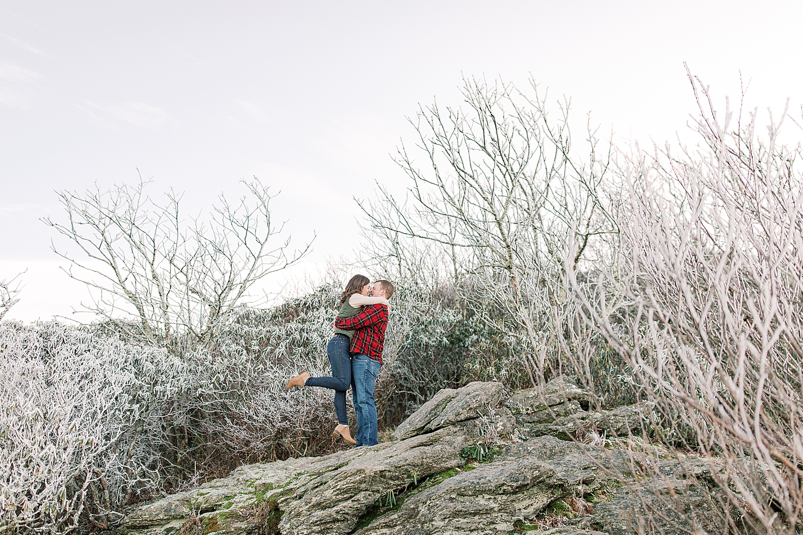 Craggy Gardens Trail Engagement Session Couple hugging and kissing on top of a rock Photo