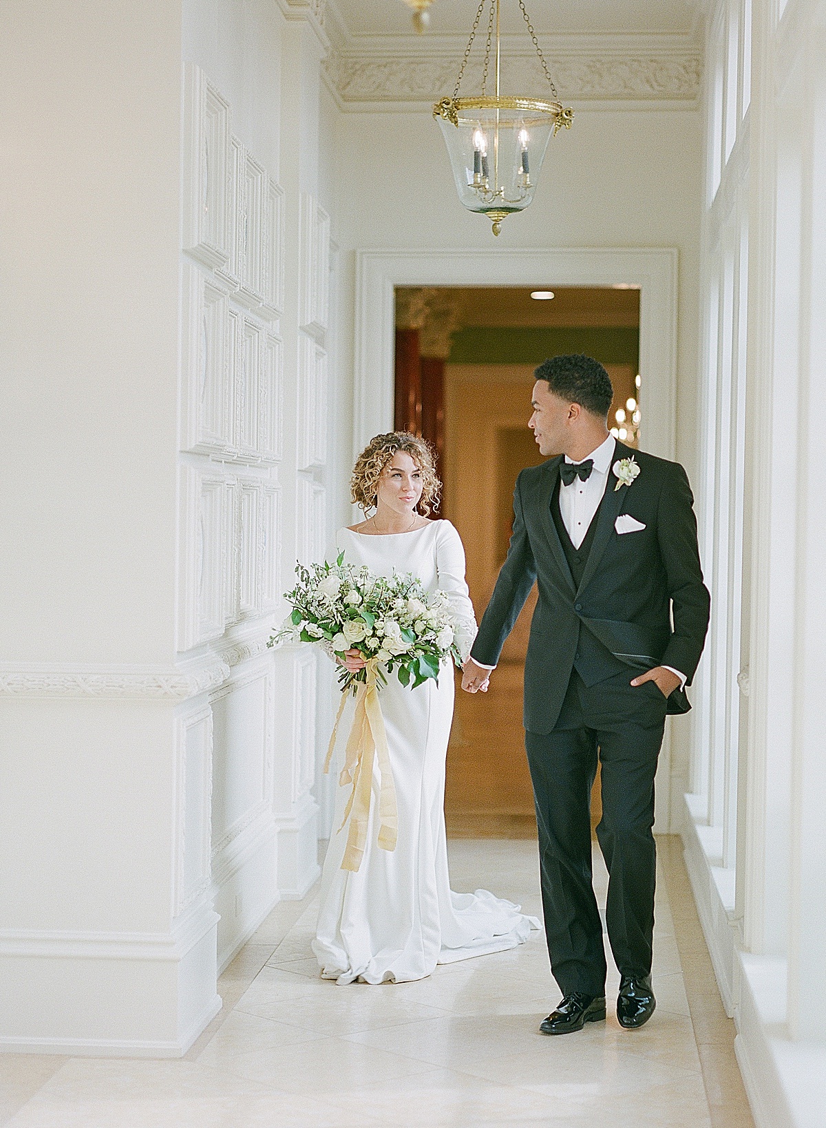 Dallas TX Wedding Venues The Olana Groom Leading Bride down White Hallway 