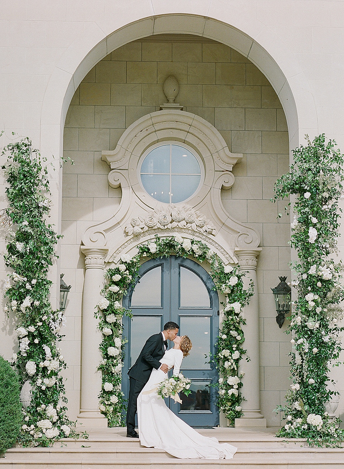 Groom Dipping and Kissing Bride In front of The Olana Wedding Venue's Grand Entrance 