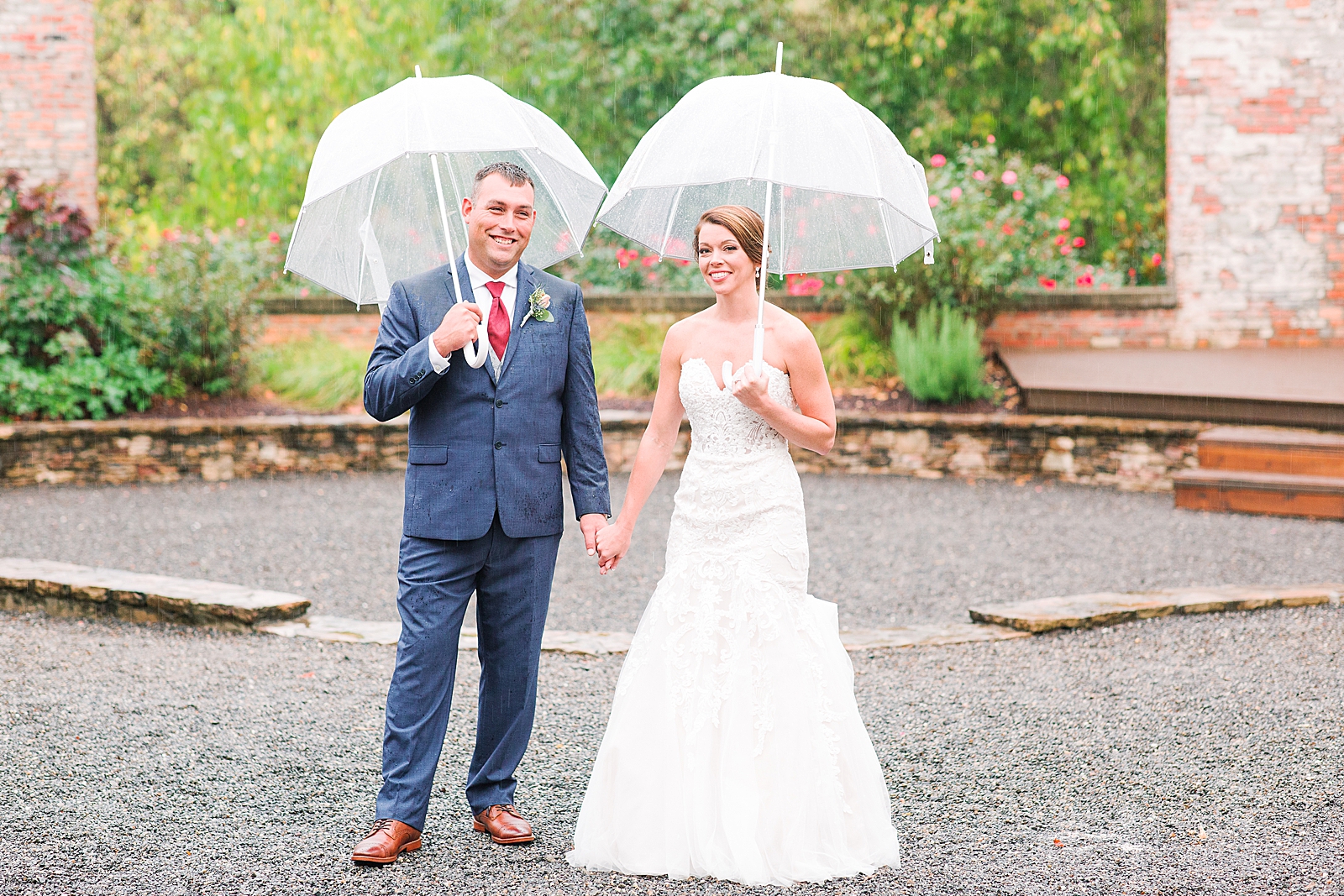 The Hackney Warehouse Bride and Groom Smiling at Camera Holding Umbrellas in Rain Photo
