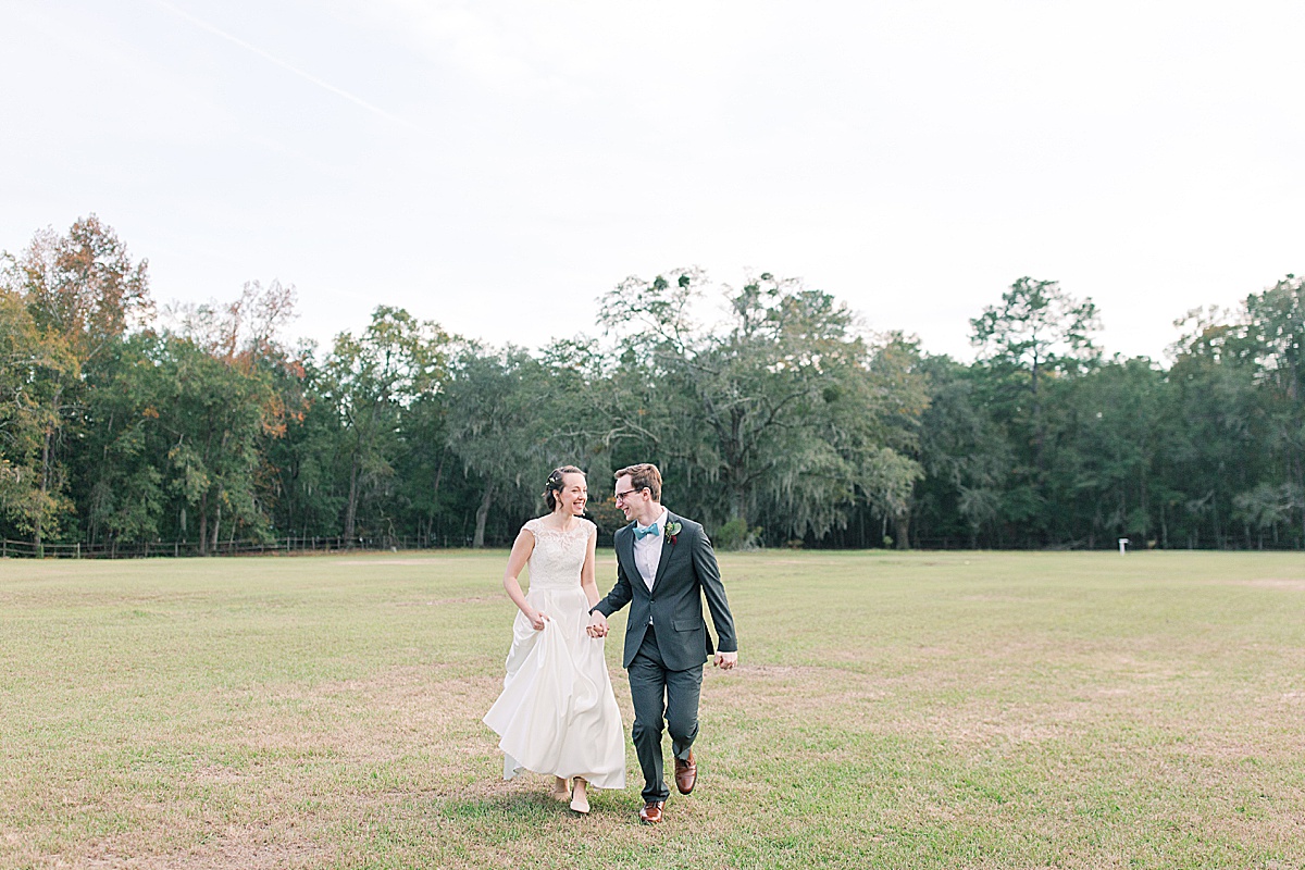 Bride and Groom Holding Hands Running Through Field 