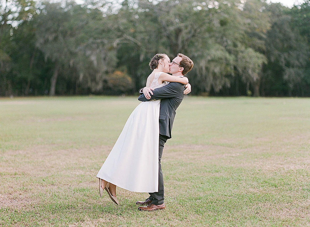Bride and Groom Hugging and Kissing in Field After Wedding 