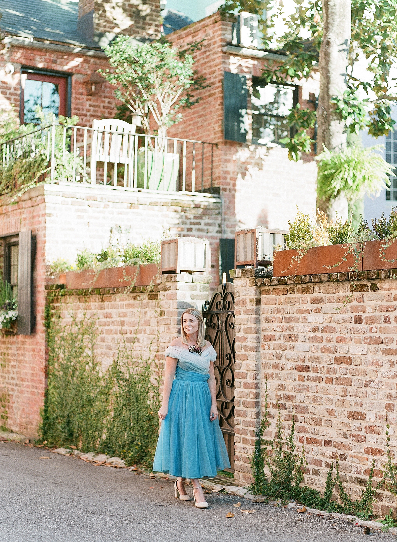Downtown Charleston Jamie in Blue Dress Walking in front of Brick Wall