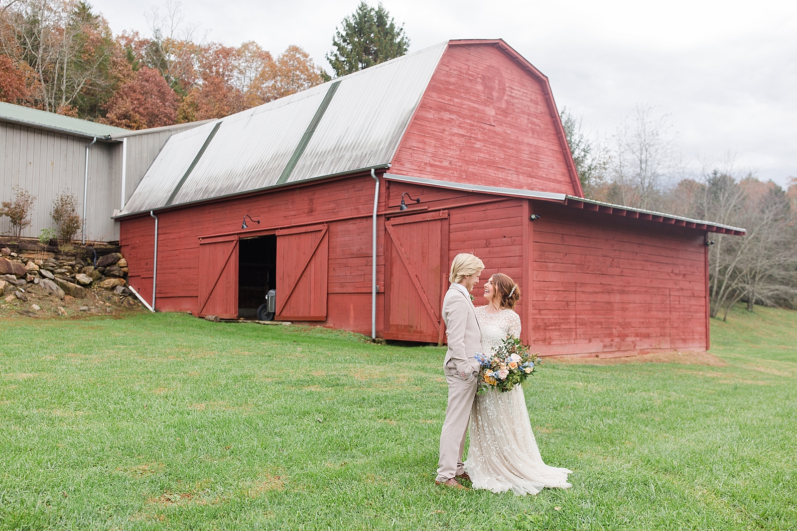 The Barn at Honeysuckle Hill Wedding Venue couple hugging In Front of Red Barn  