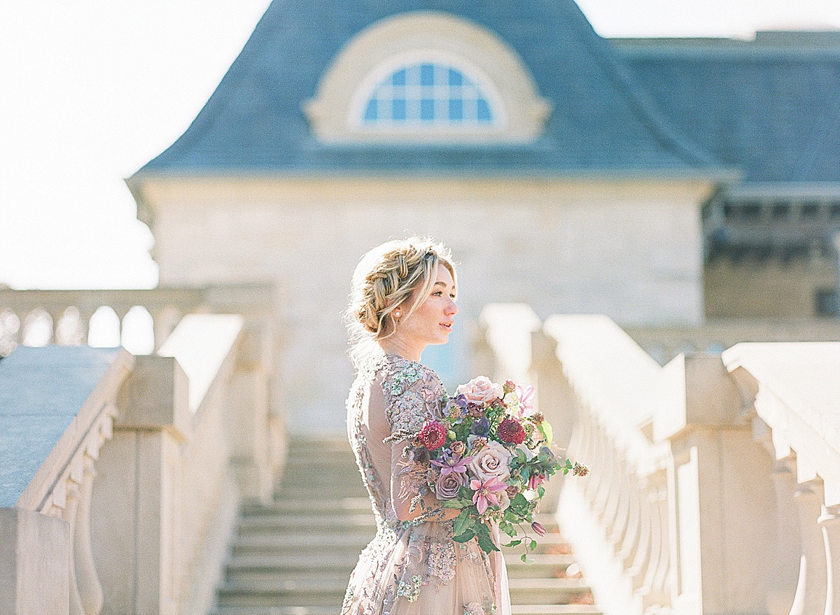 Lavender Wedding Dress Inspiration Shoot Bride on Stairs looking off holding bouquet photo 