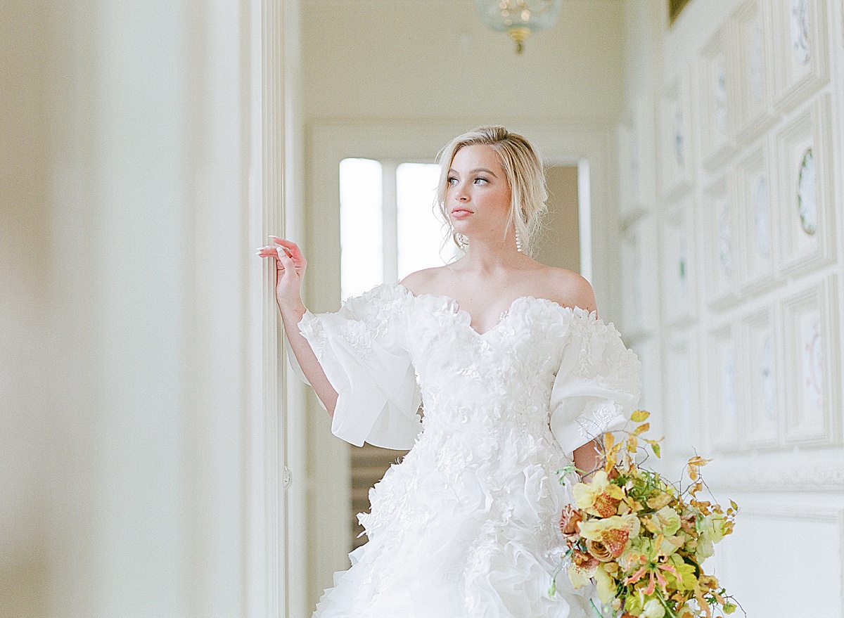 Bride Holding Yellow Bouquet Looking out Window Photo 