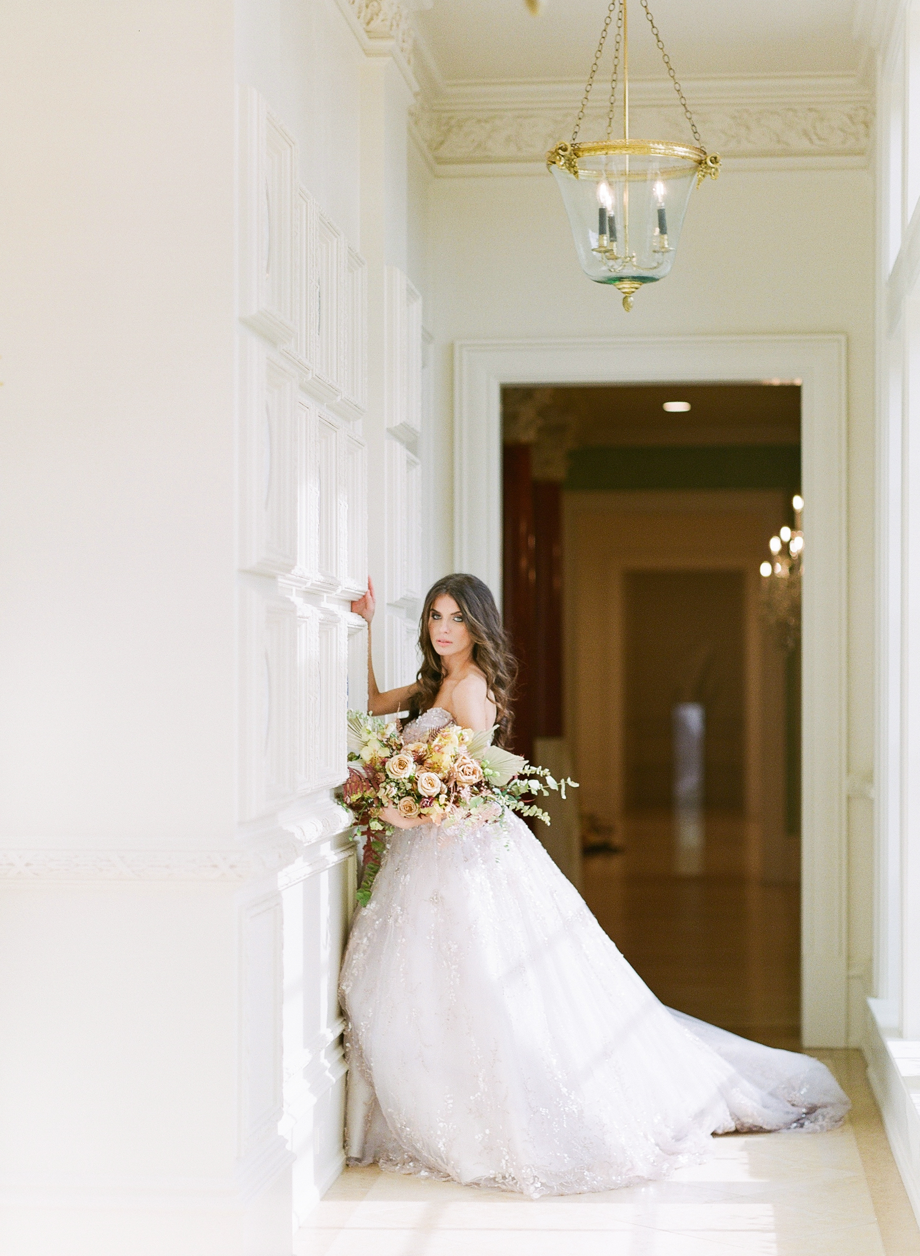 Bride in Hallway leaning against Wall Holding Bouquet Photo