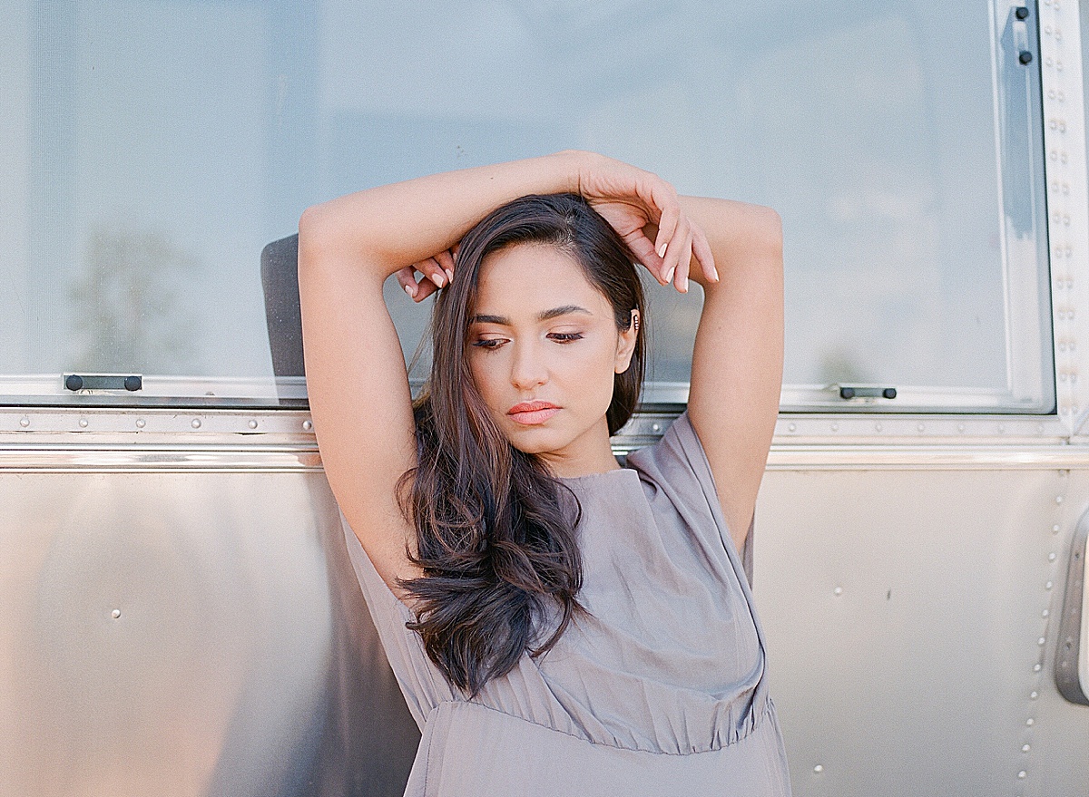 Model Looking Down With Hands On Her Head Leaning Against Airstream Photo