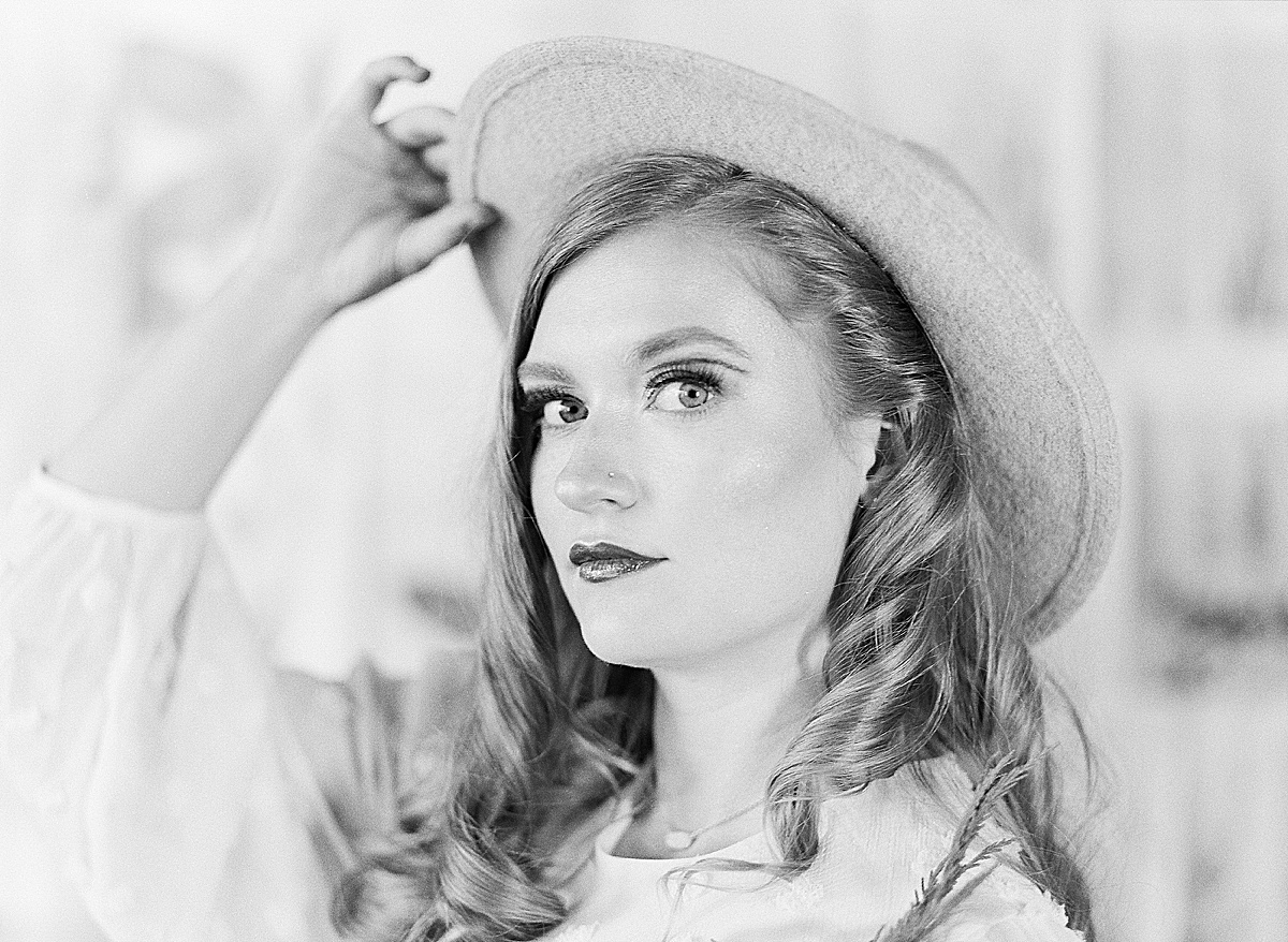 Black and White of Model Holding Brim of Hat Looking At Camera 