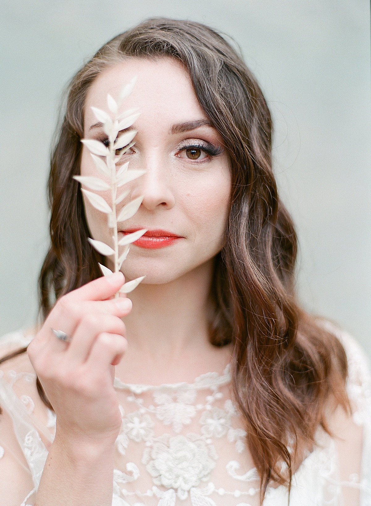 Bride holding Flower in Front of One Eye With Red Lip Stick Photo