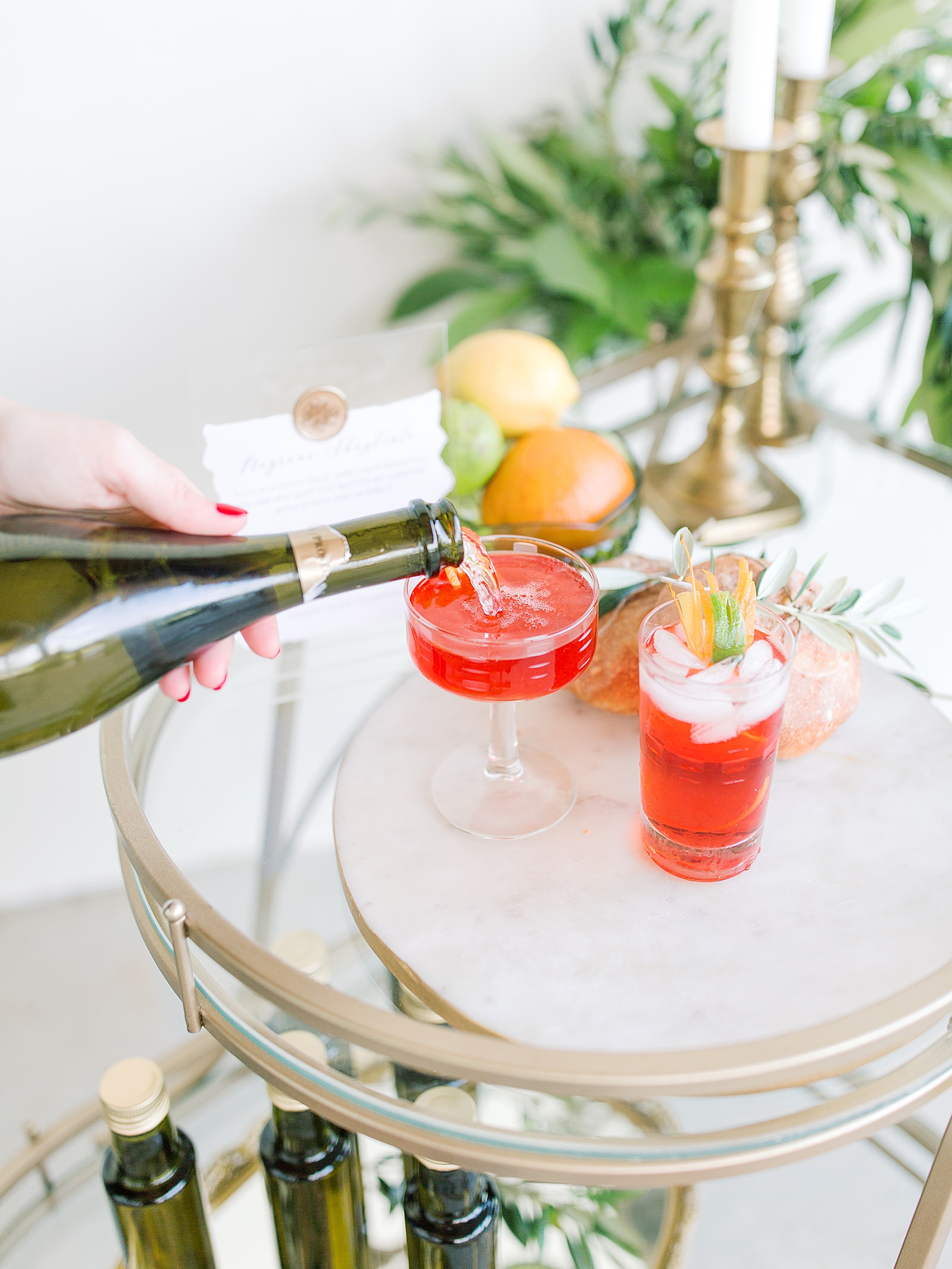 Bartender pouring champagne in Red cocktail on bar cart photo