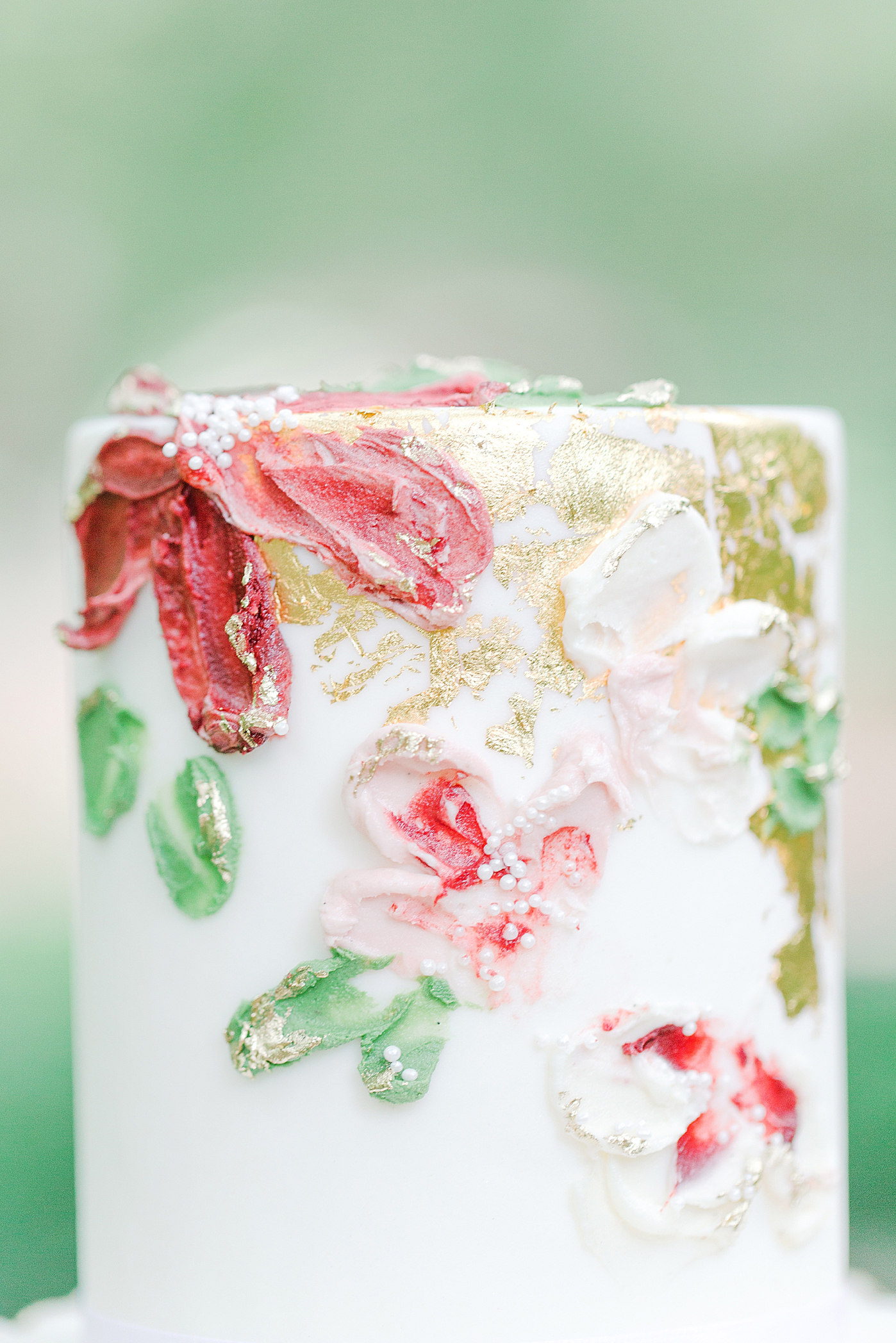 Detail of White Wedding Cake with Ruffle and Red and Pink Flowers Photo 