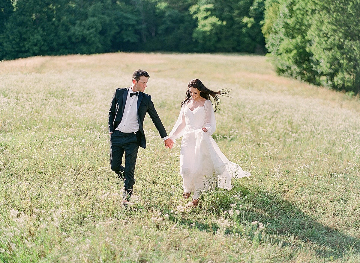 Bride and Groom walking through field holding hands