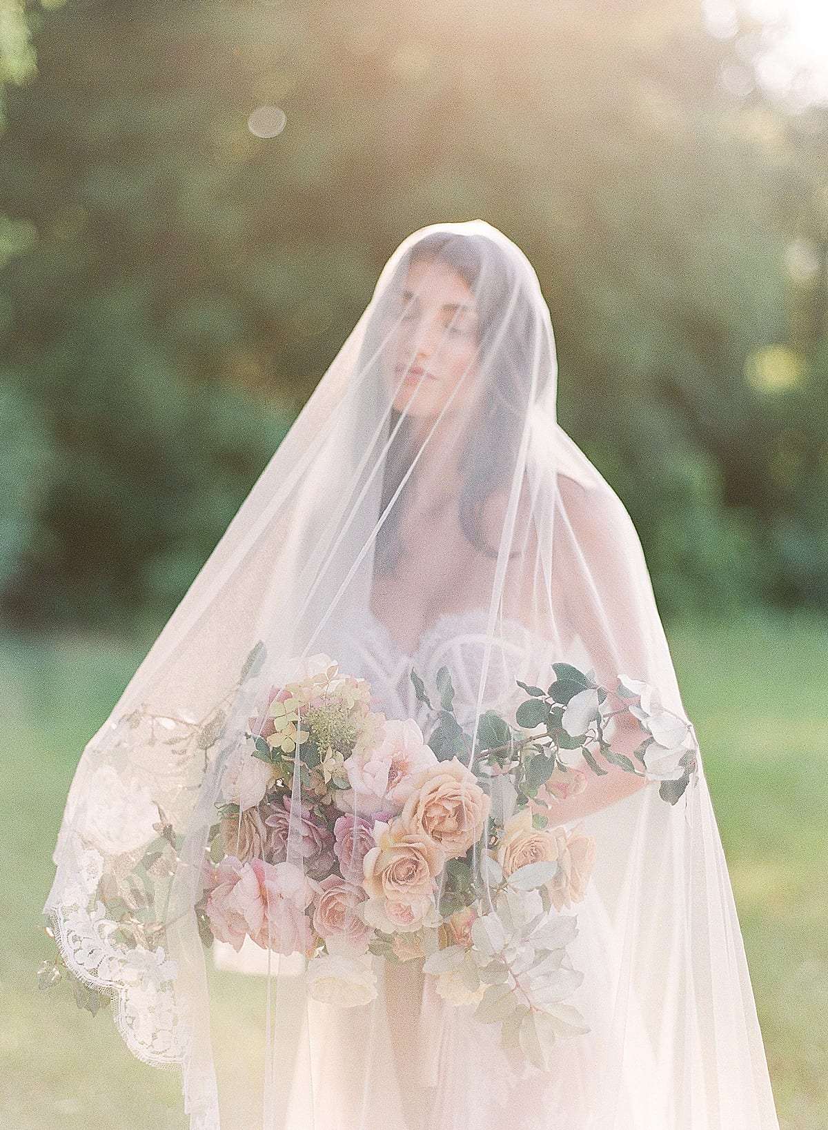 Bride with Eyes Closed Under Veil and sunlight pouring around her photo 
