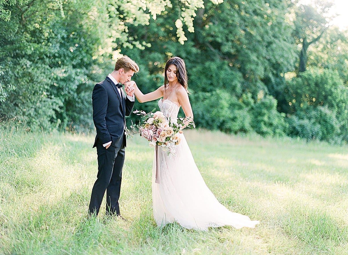 Groom Kissing Brides Hand in Field Photo 