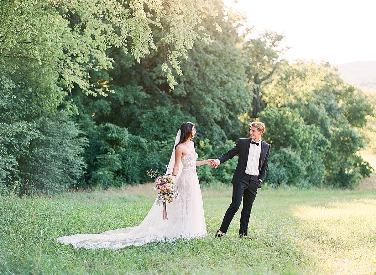 Bride and Groom at Mint Springs Farm walking in Field holding hands Photo 