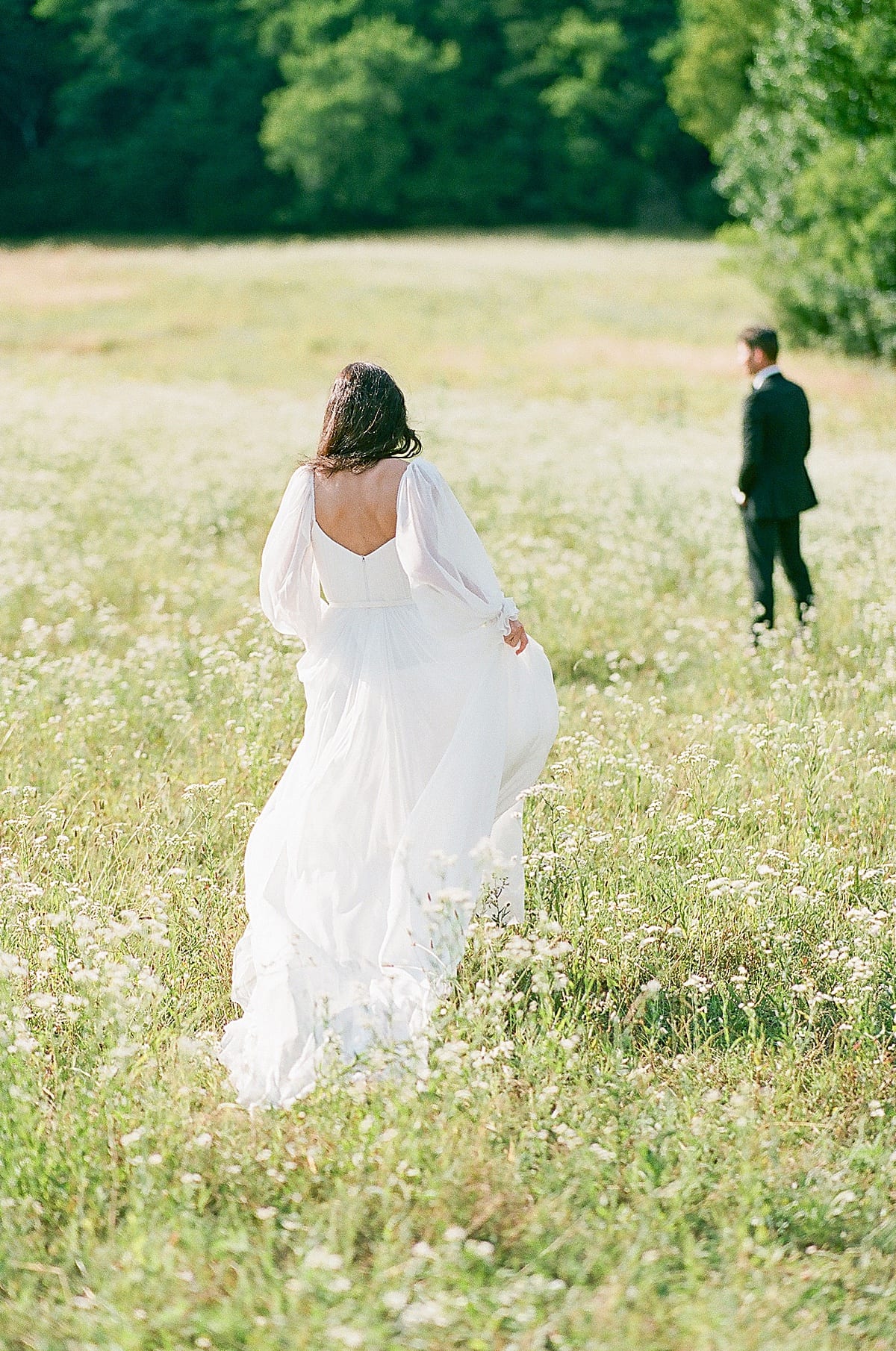 Bride walking toward groom in field photo