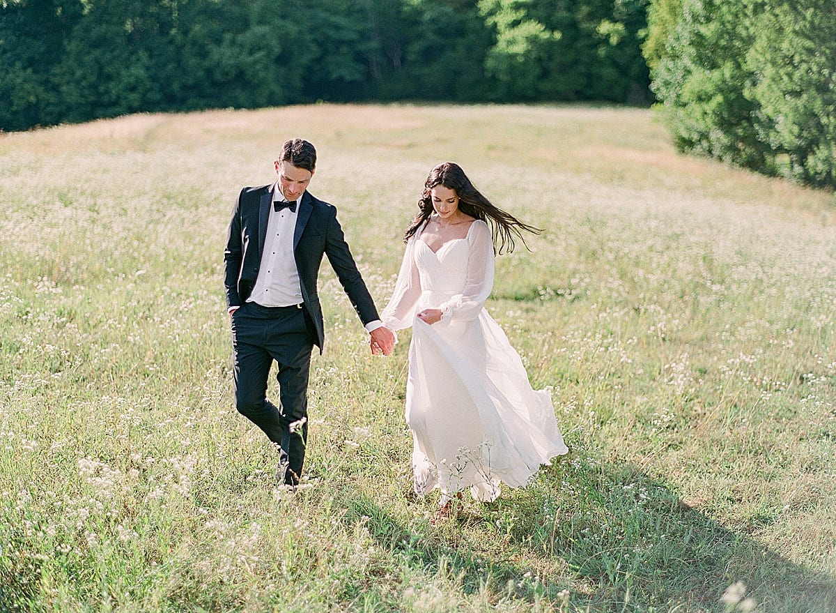 Nashville Wedding Photographer captures bride and groom walking through field photo