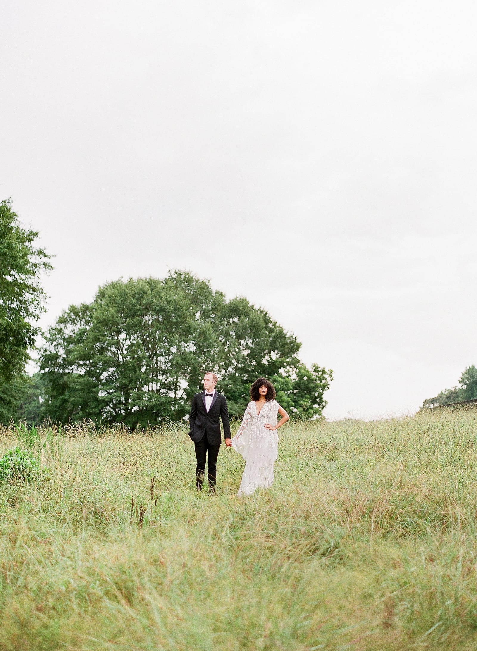 Bride and Groom Holding Hands in Field Photo