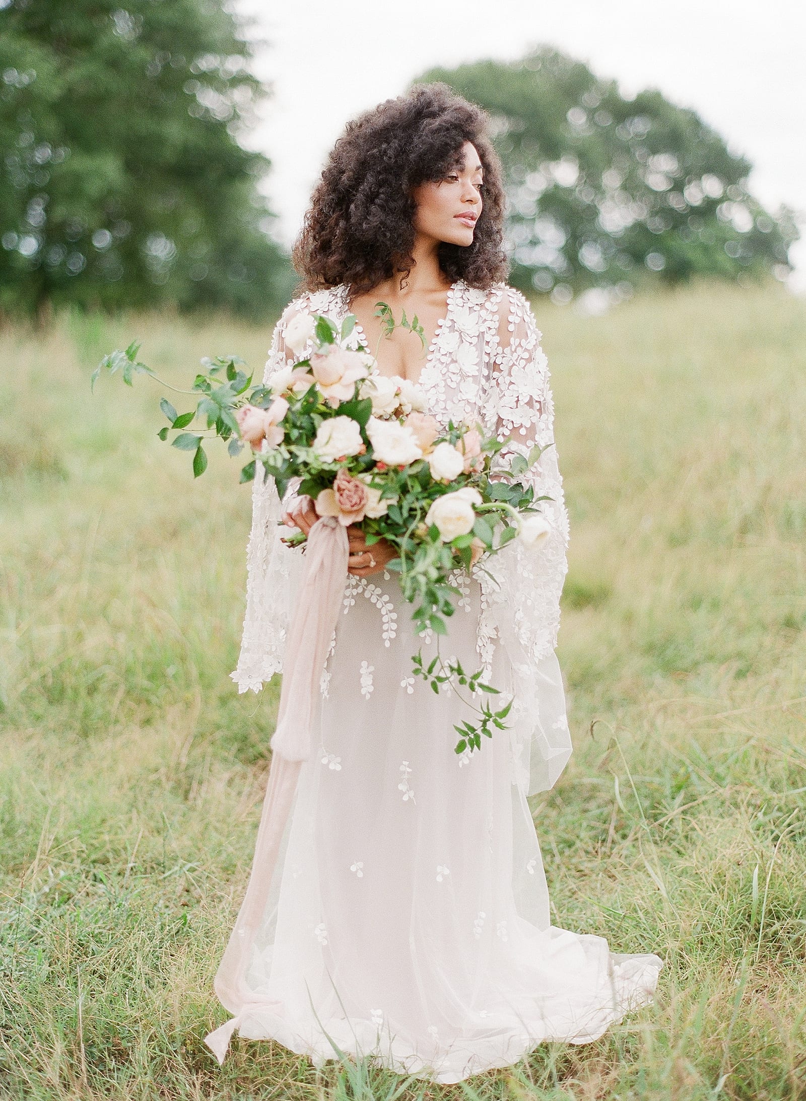 Bride in field holding Bouquet looking off Photo