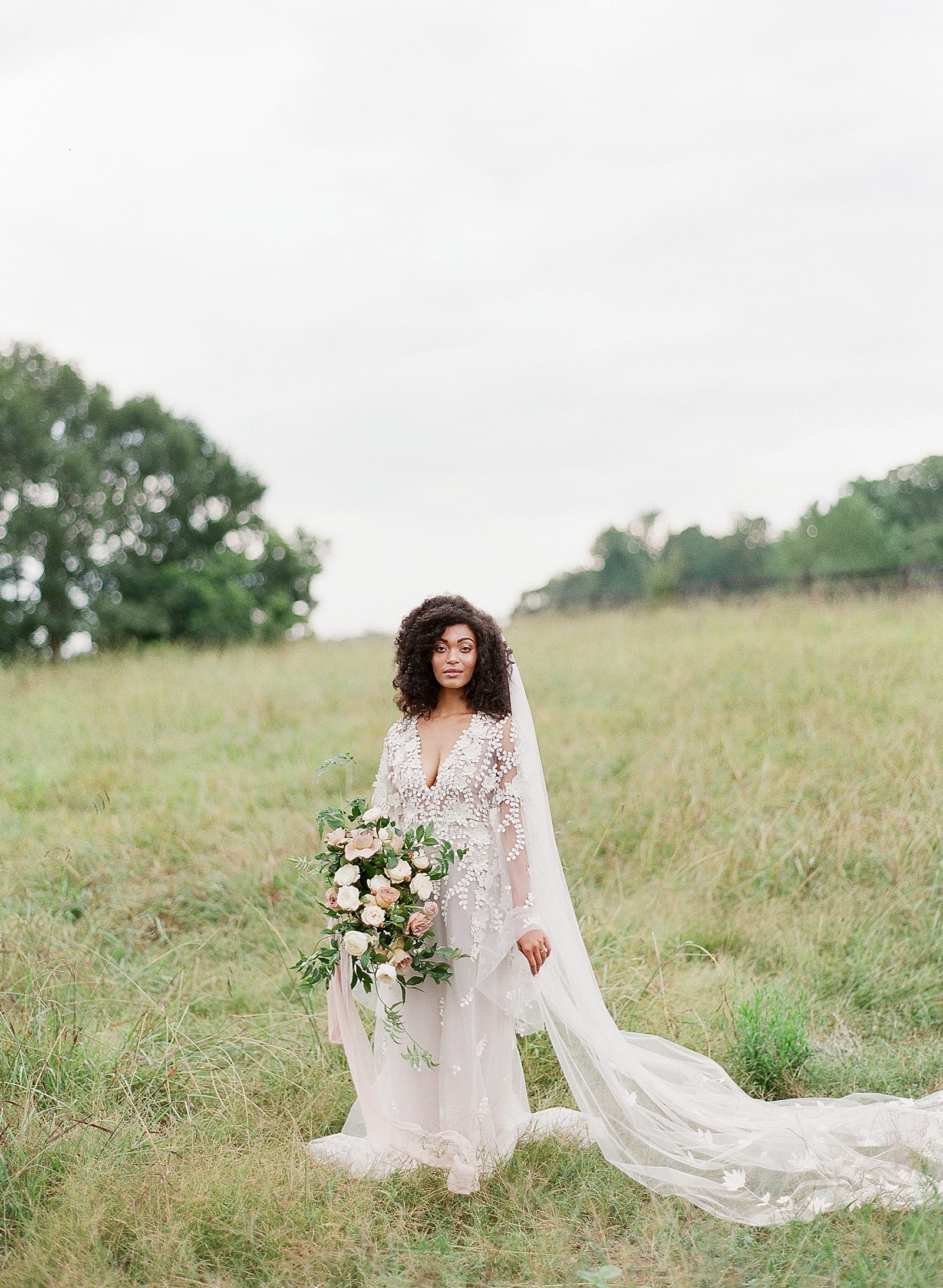 Bride with veil and bouquet in field at Inn at Serenbe Photo