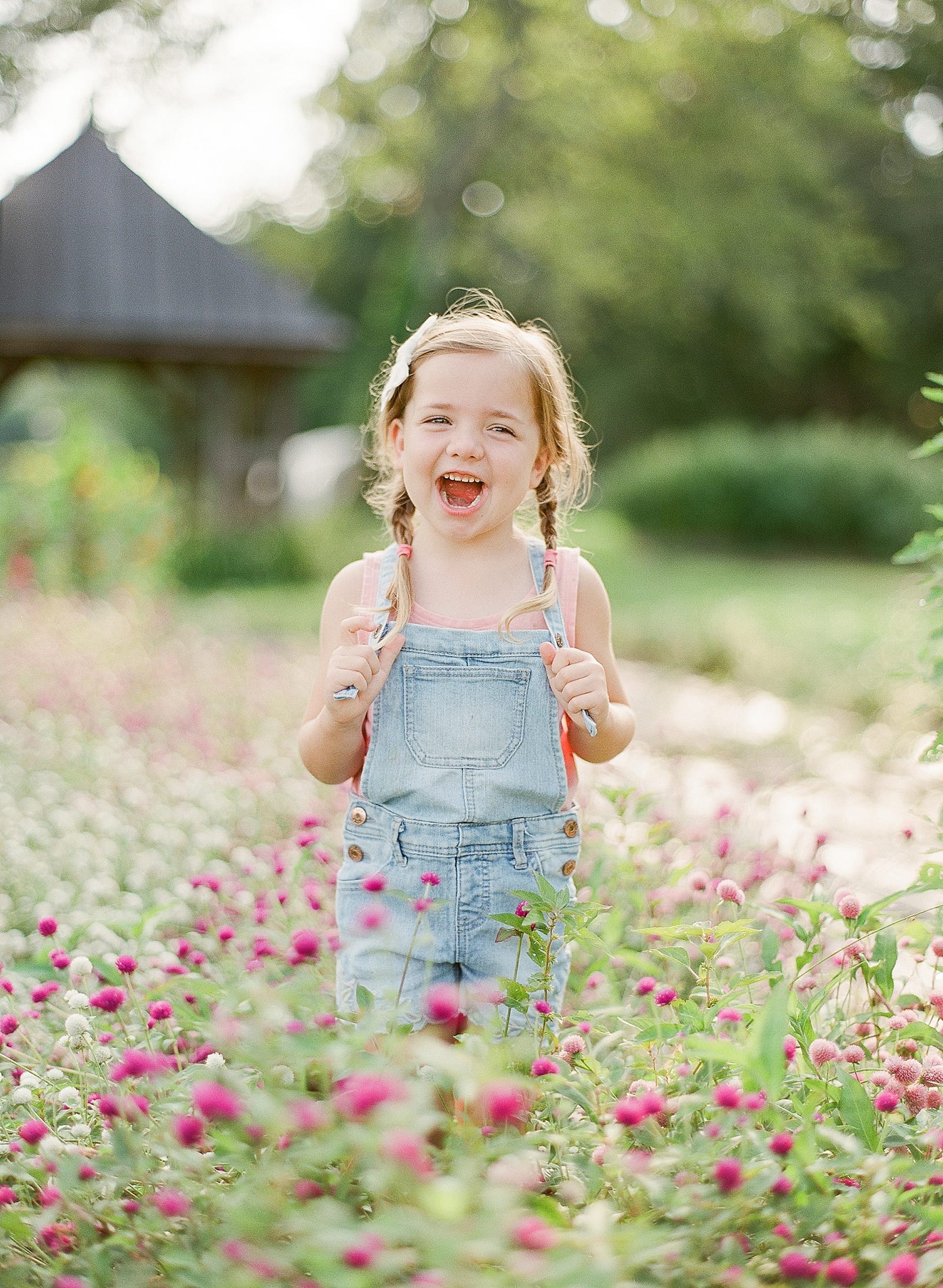 Little Girl in Overalls Laughing in Flowers Photo