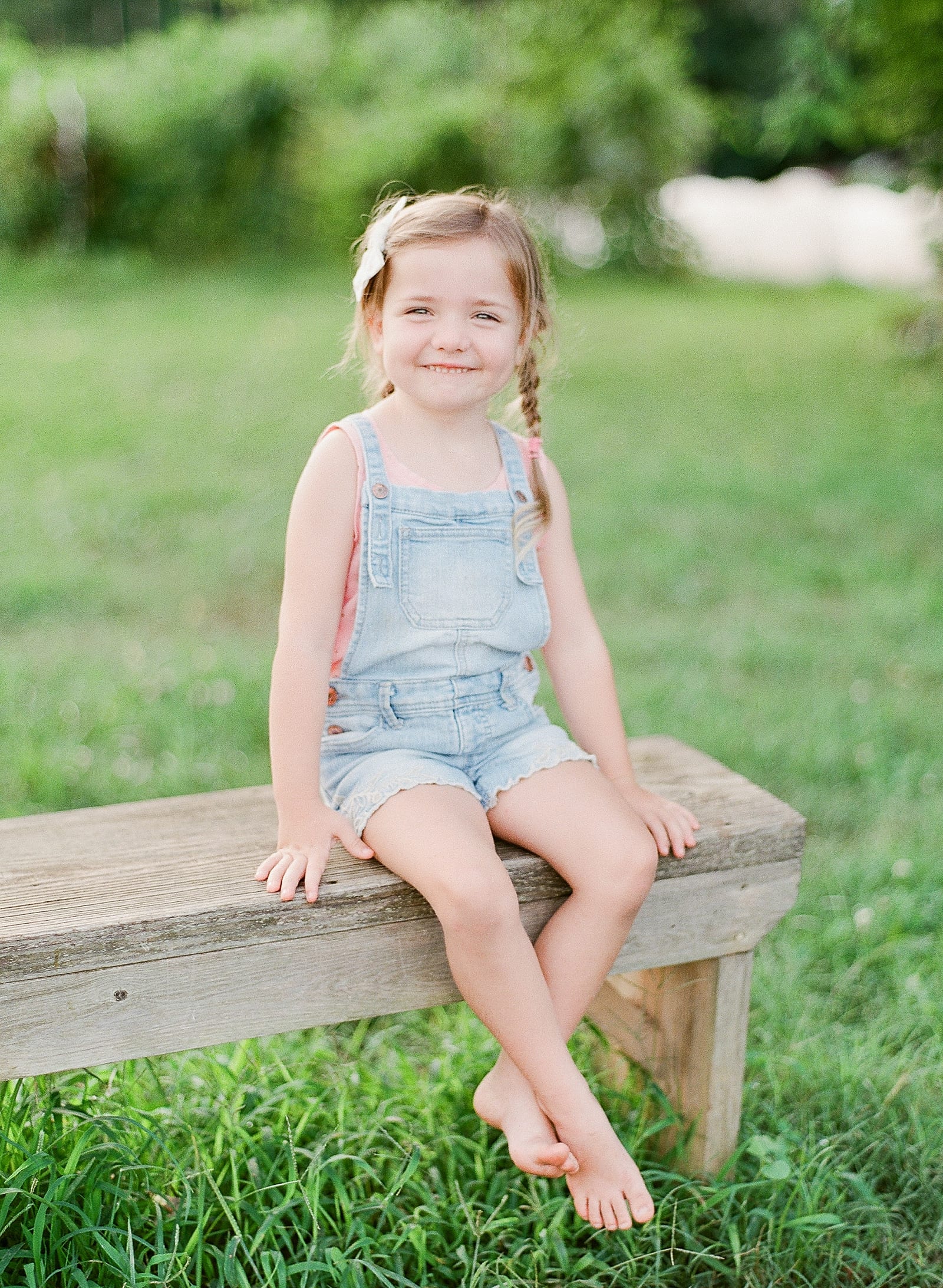 Little Girl in Overalls Sitting on Bench Photo