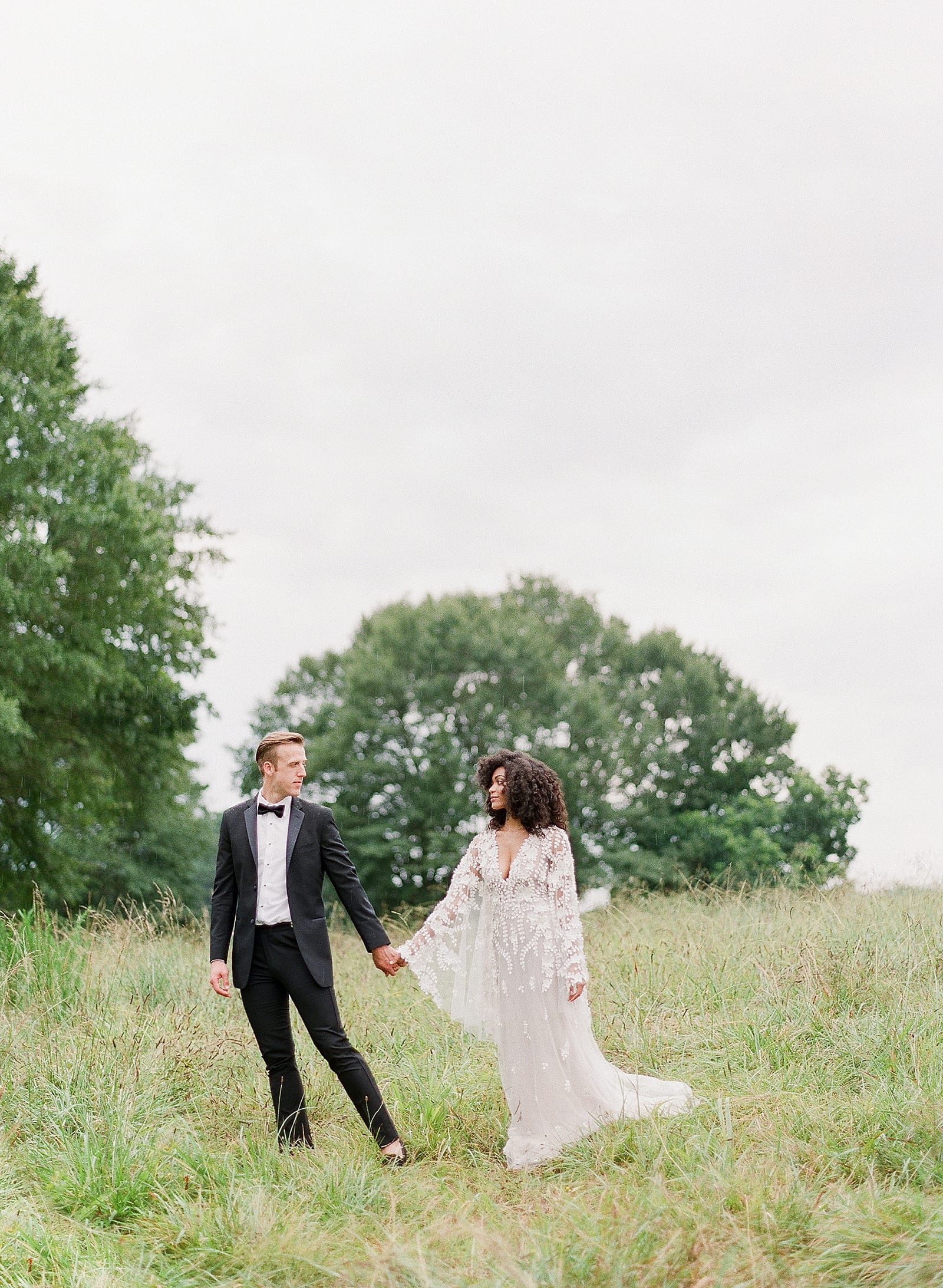 Bride and Groom Holding Hands In Field Photo