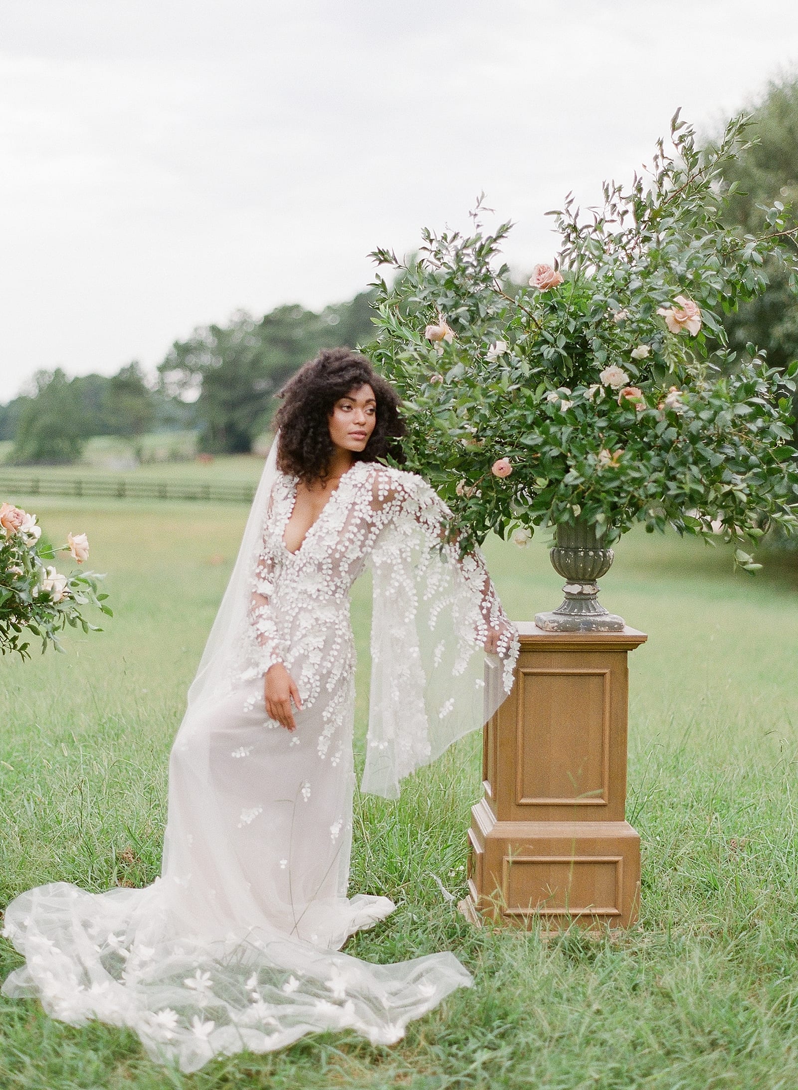 Bride Leaning on Stand with Urn of Flowers Photo