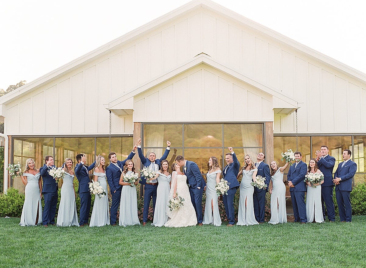 Bride and Groom Kissing and Wedding Party Cheering Photo