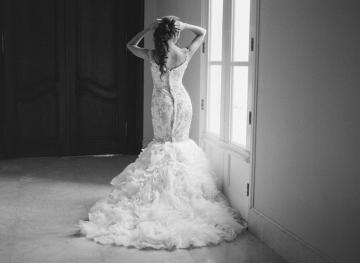 Black and White of Bride Looking Out Window With Hands On Head Photo
