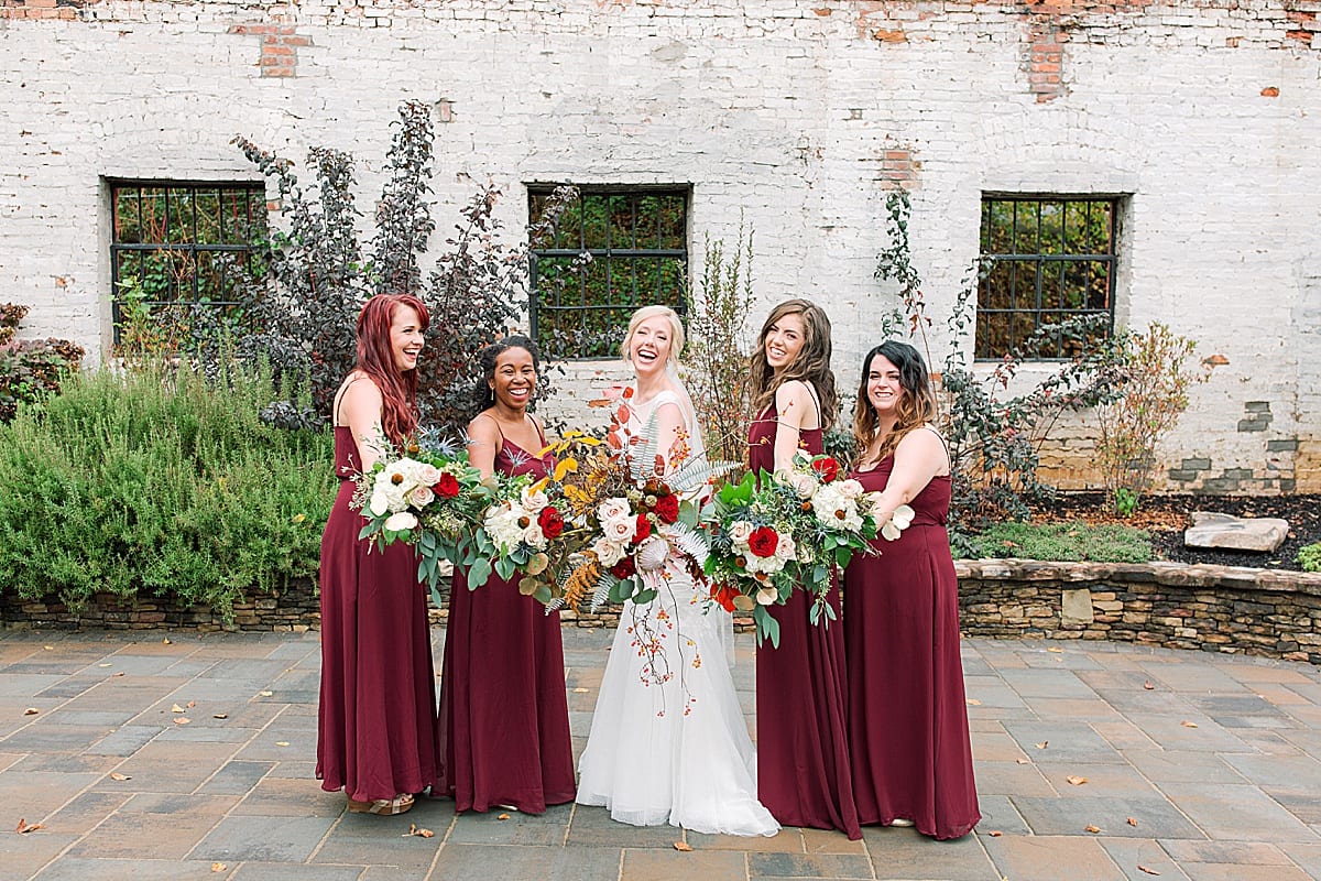 Bride with Bridesmaids in Maroon Dresses Holding Flowers Out Photo